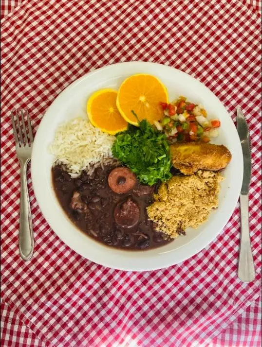 Prato de feijoada com arroz, couve, farofa e laranja no Vó Gema